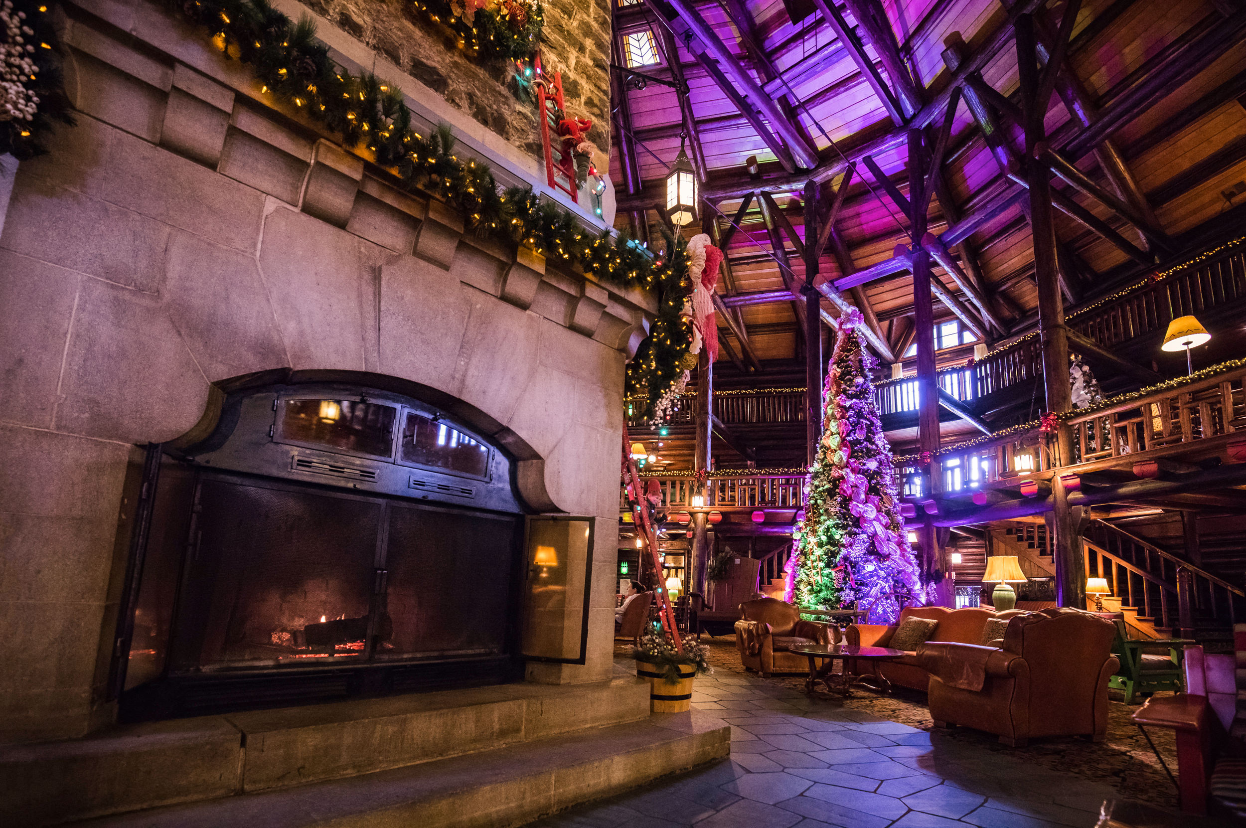 Gros plan de cheminée décorée festive avec vue sur le grand arbre de Noël