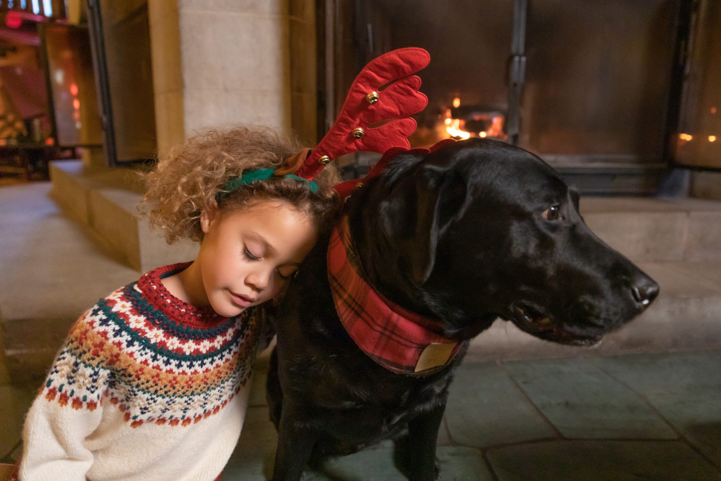 Un enfant dans les oreilles de renne étreignant un laboratoire noir