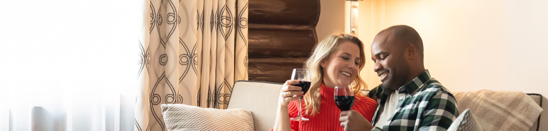 a couple sitting on a couch enjoying a glass of wine and a small charcuterie board