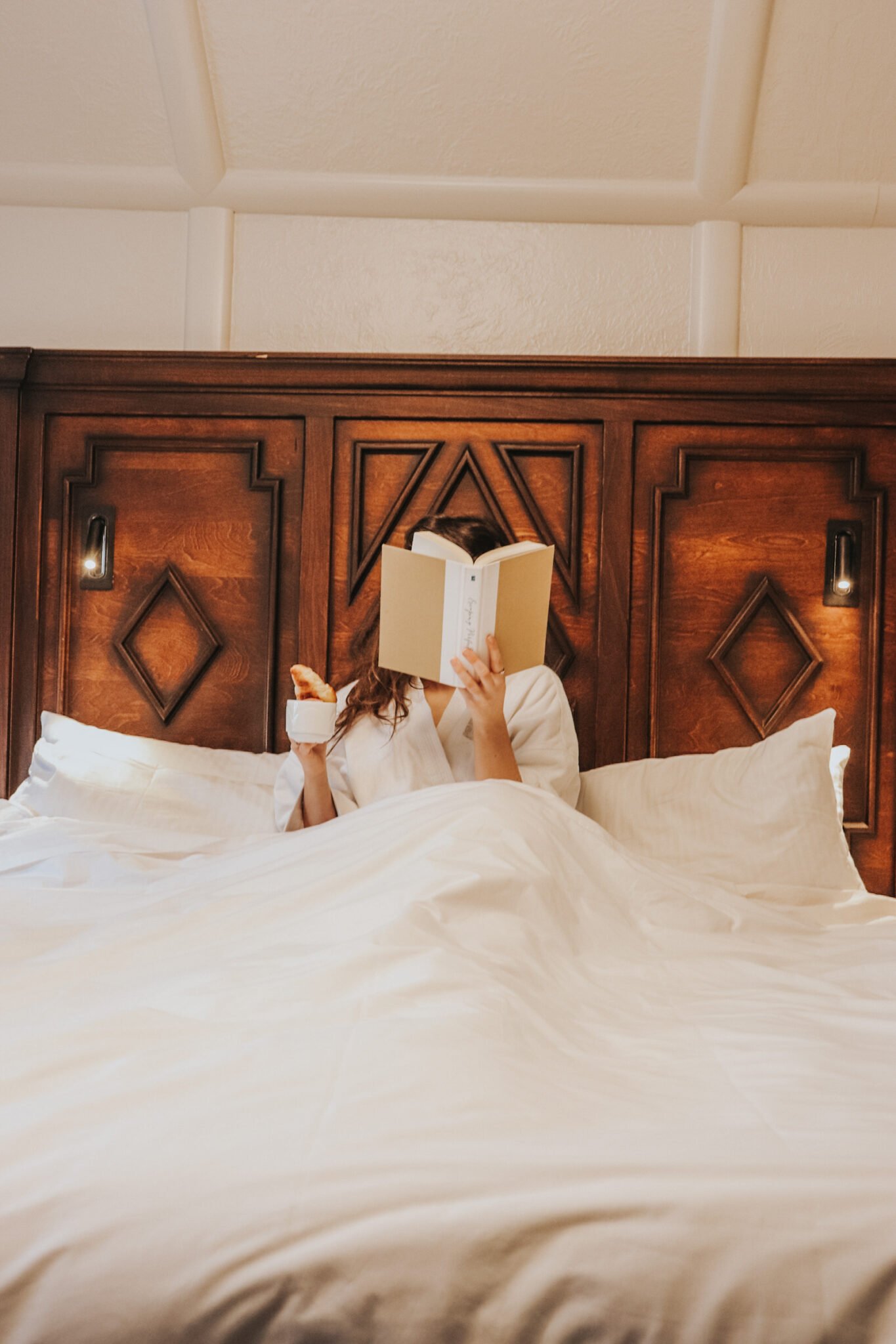 chateau montebello reading book bed blankets hotel headboard breakfast croissant